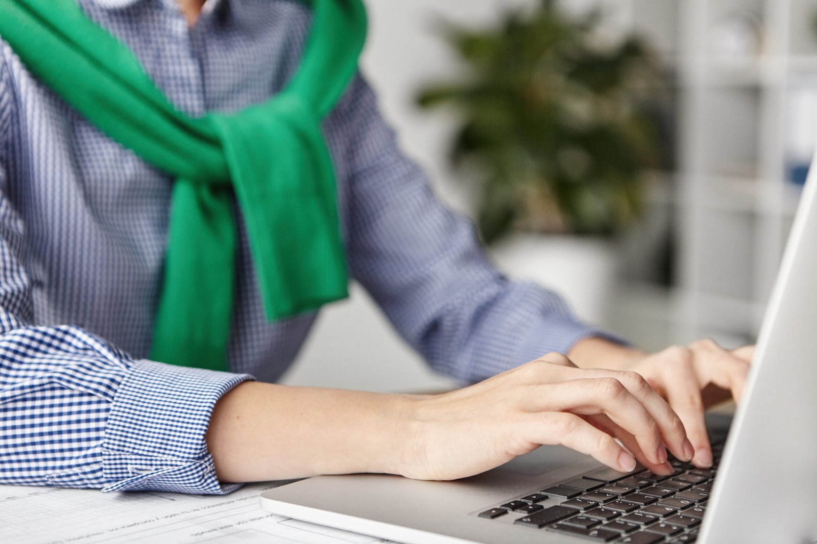 cropped shot of female`s hands types or keyboards on modern laptop computer, checks emails or makes business report, uses free internet connection, sits indoors at office or home. selective focus